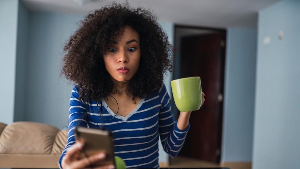 Frau schaut erschrocken aufs Smartphone
