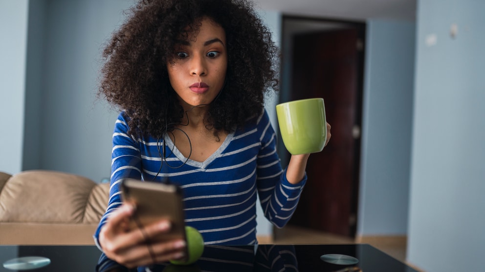 Frau schaut erschrocken aufs Smartphone