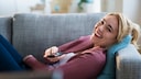 Frau lachend vor dem Fernseher