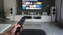 Frau sitzt mit Fernbedienung vor dem Fernseher