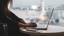 Frau arbeitet mit Laptop am Flughafen