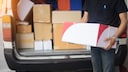 Paketbote mit Auto voller Pakete