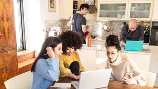 Gruppe von Freunden vor dem Handy und Laptop