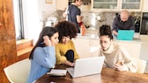 Gruppe von Freunden vor dem Handy und Laptop