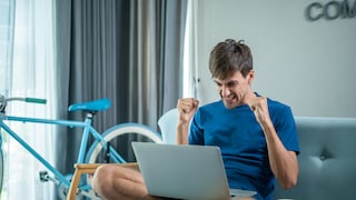 Mann sitzt jubelnd vor Laptop
