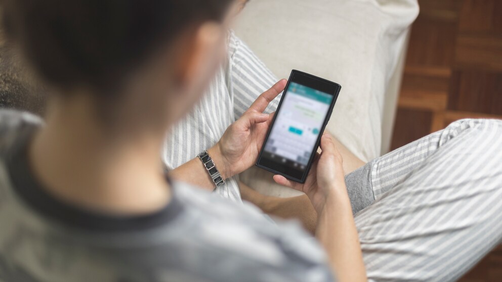 Frau chattet mit WhatsApp übers Smartphone