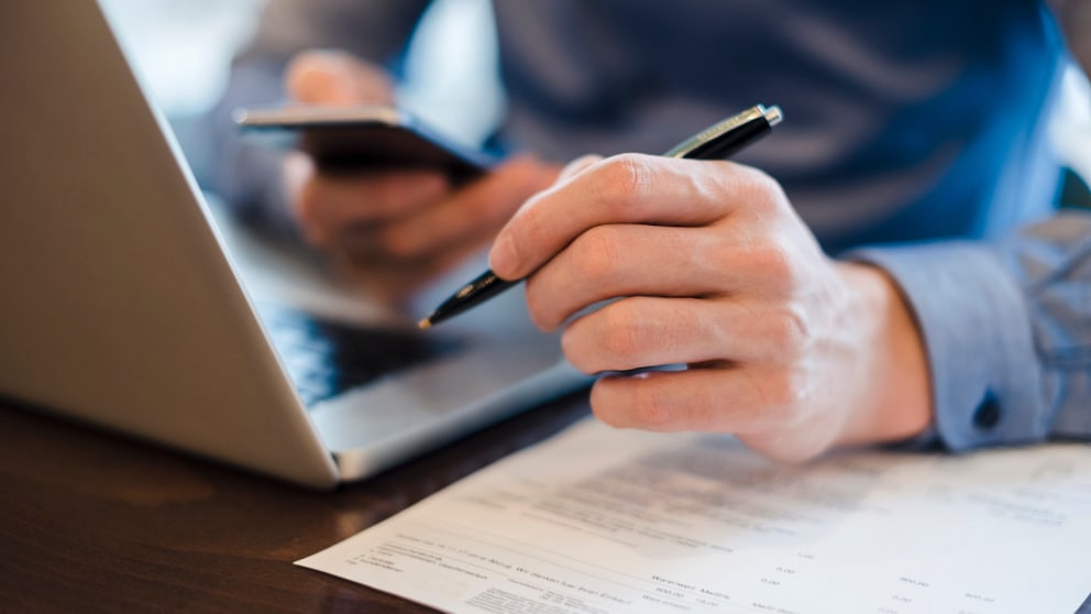 Mann am Laptop unterschreibt Vertrag