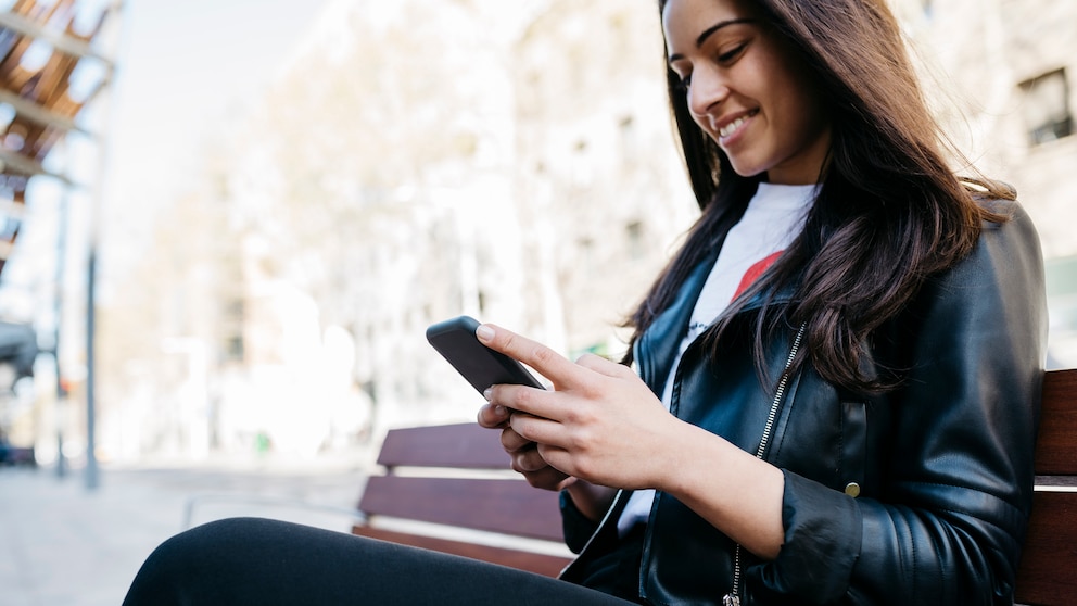 Frau mit Smartphone auf Parkbank