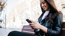 Frau mit Smartphone auf Parkbank