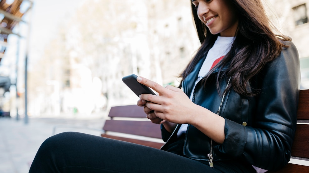 Frau mit Smartphone auf Parkbank