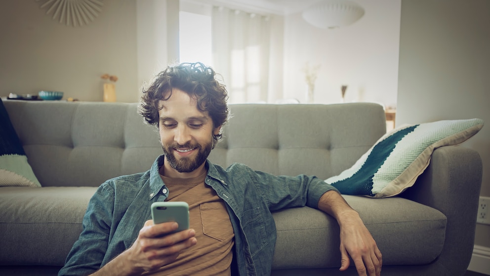 Mann mit Smartphone im Wohnzimmer
