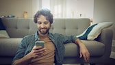 Mann mit Smartphone im Wohnzimmer