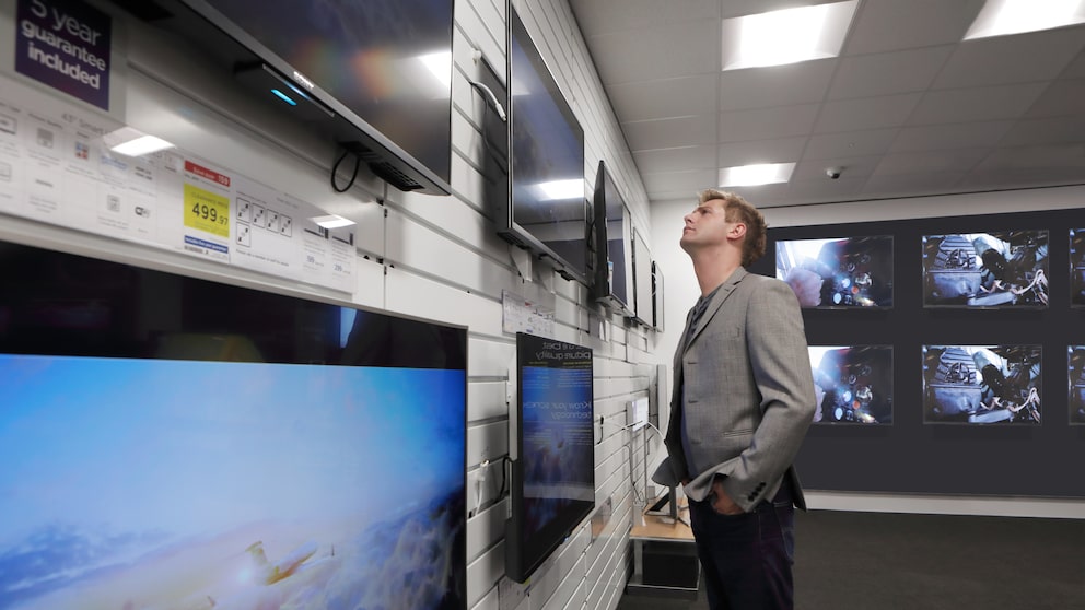 Man im Elektronikladen vor den Fernsehern