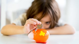 Kind steckt Geld ins Sparschwein