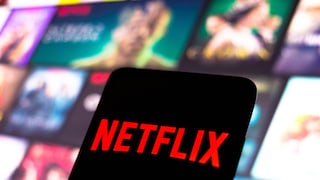 Netflix-Logo auf einem Handy, im Hintergrund Streaming-Kacheln.