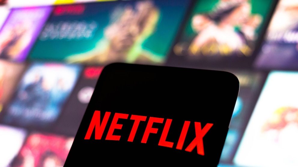 Netflix-Logo auf einem Handy, im Hintergrund Streaming-Kacheln.