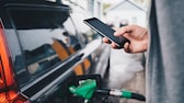 Spritpreise online: Mann mit Handy an der Tankstelle