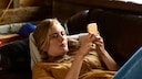 Instagram Story Funktion: junge Frau mit Handy auf dem Sofa