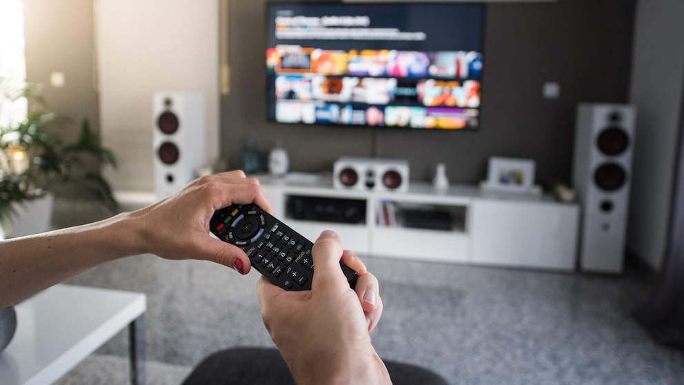 Netflix und Disney+: Zwei Leute greifen nach einer Fernbedienung