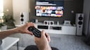 Netflix und Disney+: Zwei Leute greifen nach einer Fernbedienung
