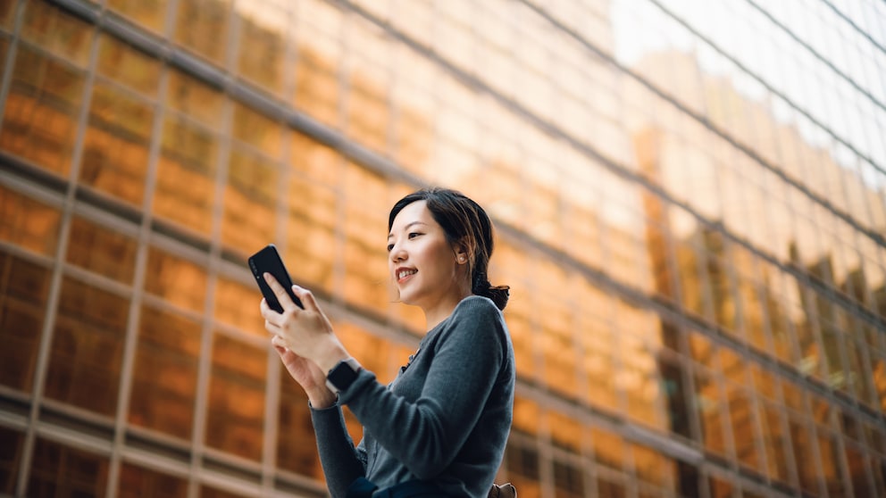 Frau mit Handy: iPhone auf Rückseite tippen