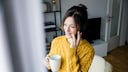 Frau am Fenster telefoniert