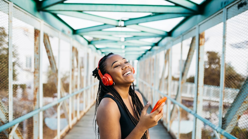 Bluetooth Auracast: Junge Frau hört via Bluetooth-Kopfhörer Musk