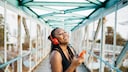 Bluetooth Auracast: Junge Frau hört via Bluetooth-Kopfhörer Musk