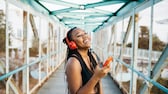 Bluetooth Auracast: Junge Frau hört via Bluetooth-Kopfhörer Musk