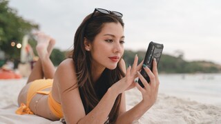 Frau am Strand mit Smartphone