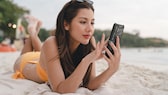 Frau am Strand mit Smartphone