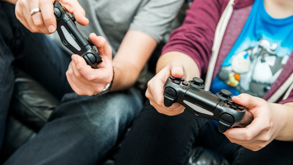 Konsole kühlen: Zwei Männer spielen zusammen PlayStation