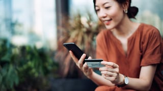 Frau tätigt Überweisung ins Ausland per App mit Smartphone und Kreditkarte