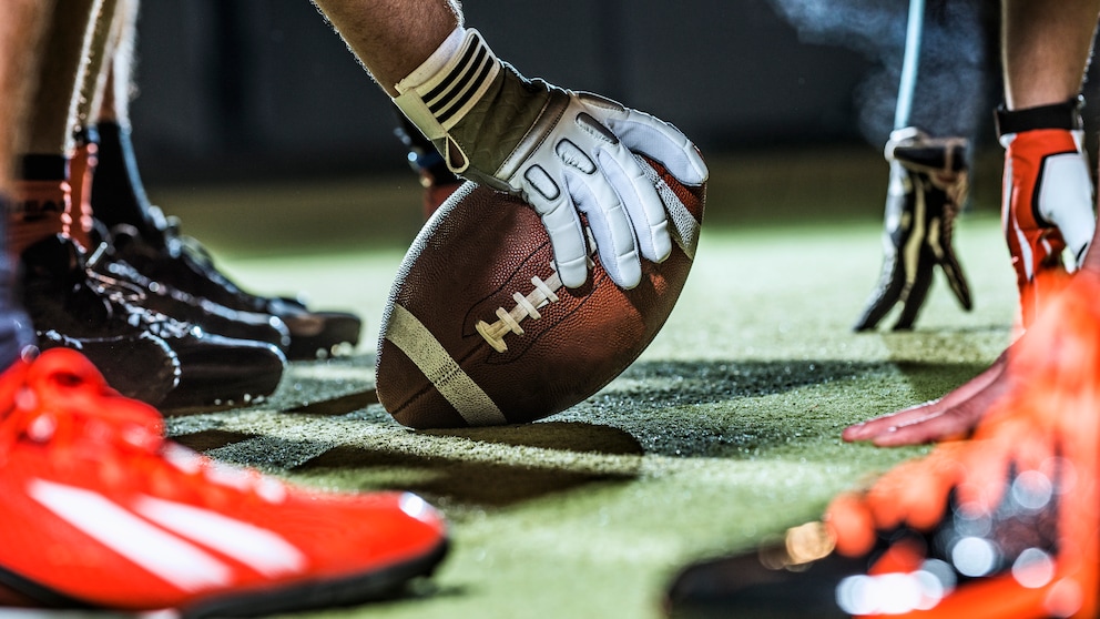 Football in Hand auf Spielfeld: NFL-Spiele im Stream