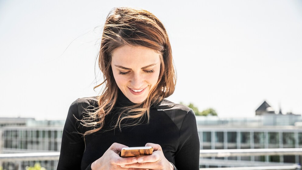 Frau schaut lächelnd aufs Smartphone