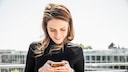 Frau schaut lächelnd aufs Smartphone