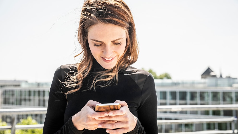 Frau schaut lächelnd aufs Smartphone