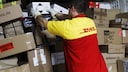 DHL-Fahrer sortiert Pakete