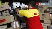 DHL-Fahrer sortiert Pakete