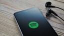Spotify Logo auf Smartphone mit Kopfhörern