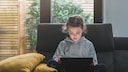 Kleines Mädchen auf dem Sofa mit Tablet.