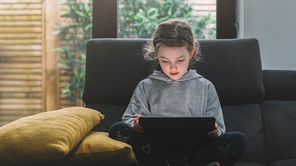 Kleines Mädchen auf dem Sofa mit Tablet.