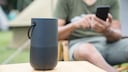 Bluetooth-Box im Vordergrund, hinten Mann mit Smartphone Bluetooth Boxen Stiftung Warentest