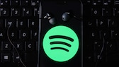 Spotify Logo auf Smartphone mit Kopfhörern auf Tastatur wegen Preiserhöhung