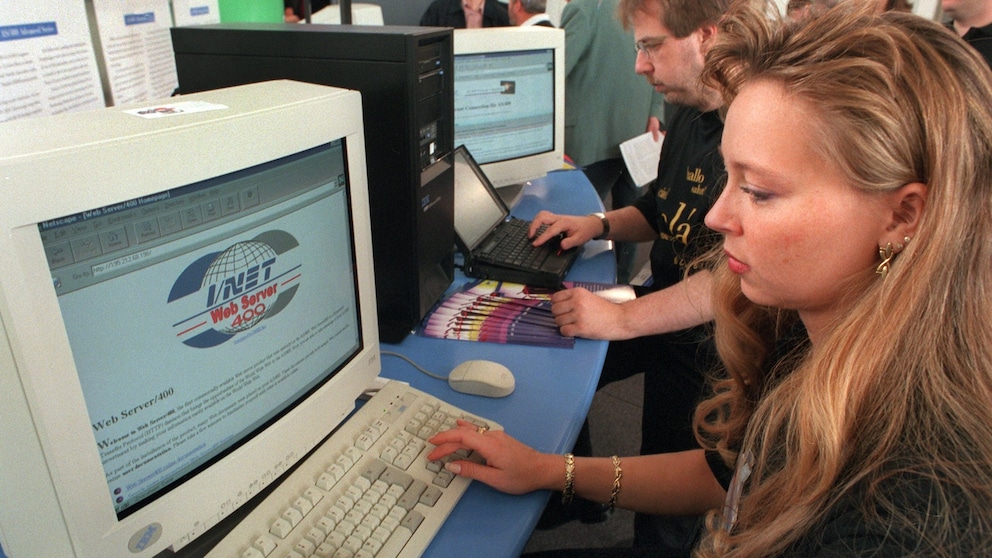 Junge Frau sitzt in den 90er an einem Röhren-Bildschirm und surft mit einem PC im Internet.