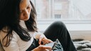 Frau schaut konzentriert auf Smartphone