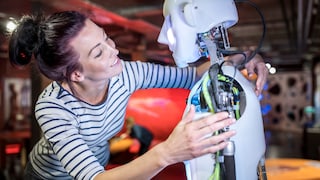 Frau beugt sich zu Roboter der menschenähnlich aussieht