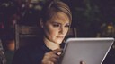 Frau schaut ernst aufs Tablet
