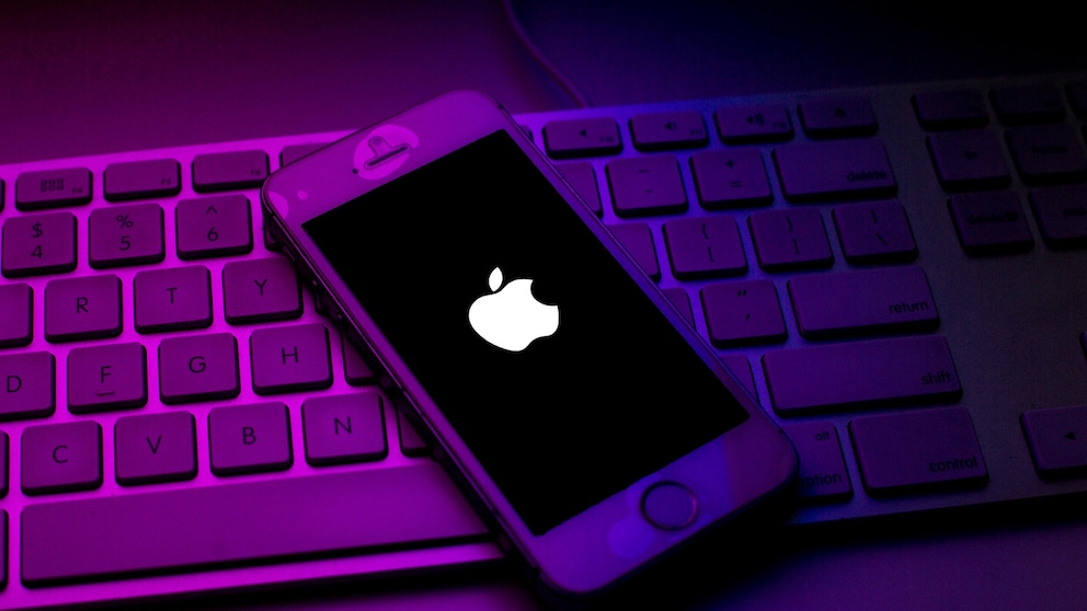iPhone mit Apple-Logo auf Tatstatur. Apple steht in der Kritik App-Tracking in eigenen Apps mit fehlender Berechtigung zu betreiben.