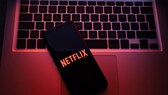 Smartphone auf einer Mac-Tastatur mit Netflix-Logo. Netflix-Account bietet Funktion zum ausloggen einzelner Geräte.